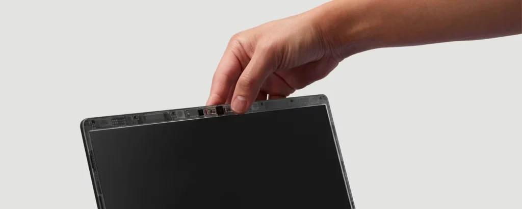 Framework Laptop 13 Pro display panel being removed by hand showing detachable screen design with visible connectors and modular repair-friendly construction