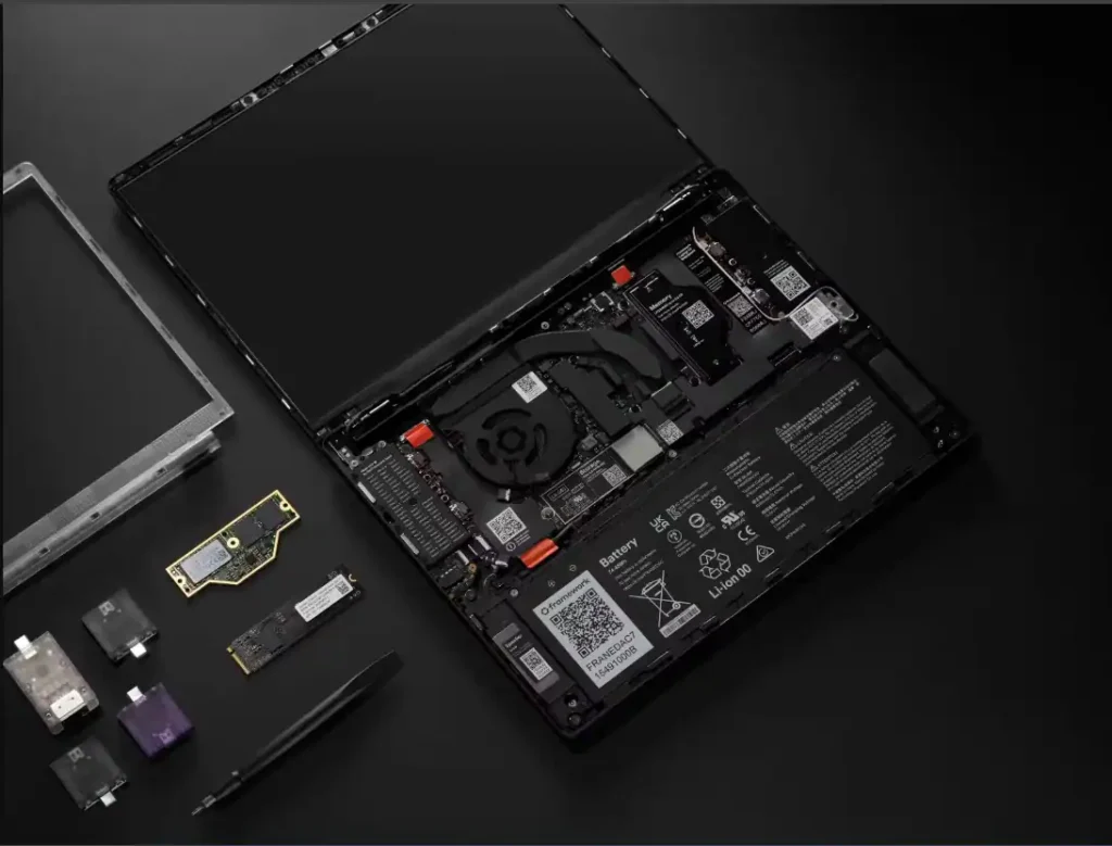 Framework Laptop 13 Pro opened from top view displaying internal components such as battery, cooling system, motherboard, and modular expansion cards placed nearby