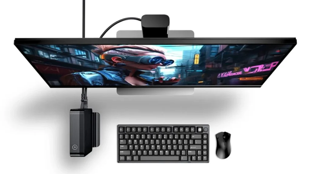 GPD BOX mini PC mounted behind a monitor in a clean desk setup with keyboard and mouse, demonstrating compact form factor and cable management