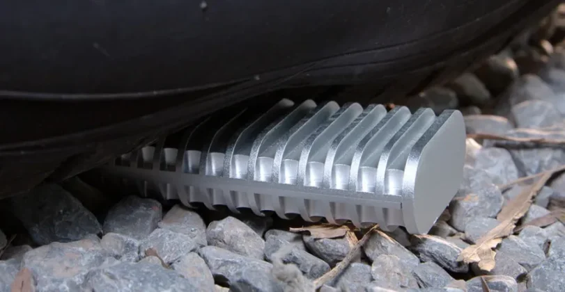 TerraMaster D1 rugged SSD enclosure placed under heavy pressure on gravel surface showing durable metal body and impact resistance