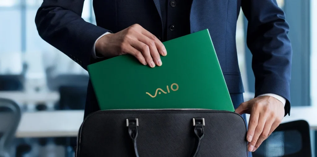 VAIO SX14-R VJS4R2 green laptop being placed into a bag by a professional user, highlighting portability, compact size, and premium aluminum build