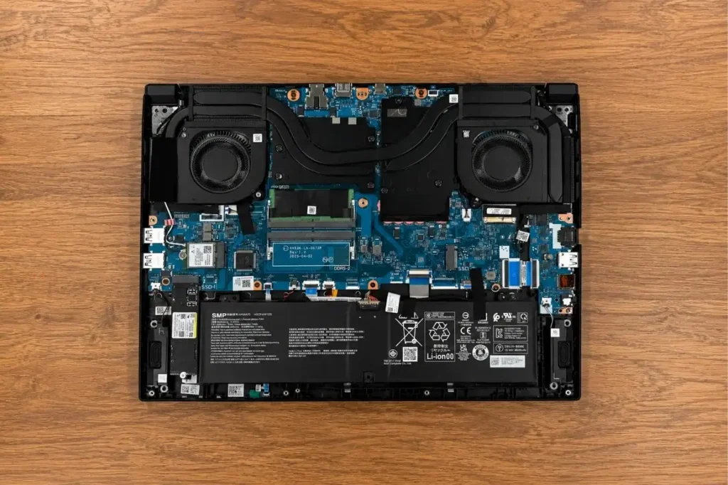 Internal view of Acer Nitro V 16 AI gaming laptop showing dual-fan cooling system, heat pipes, motherboard, and battery layout.