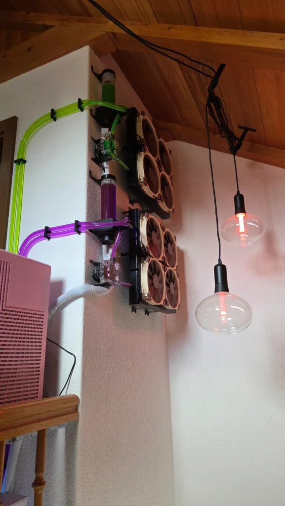 Wall-mounted radiator array with pumps, reservoirs, and coolant tubing connected to gaming PCs