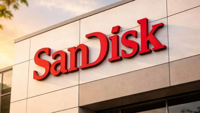 SanDisk sign photographed against a clear blue sky, partially obscured by green leaves in the foreground.