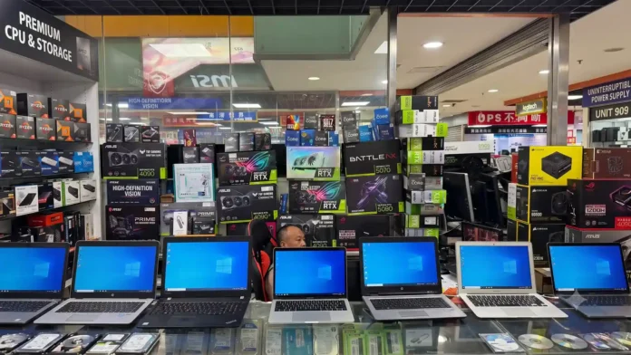 Front counter of a computer shop displaying laptops and stacked GPU boxes in Chengdu's Computer City retail market.