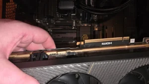 A hand holding the ZOTAC GeForce RTX 5090 SOLID graphics card next to the primary PCIe connection slot.