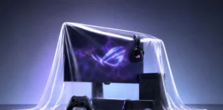 ASUS ROG Announced New Controller, Monitor, Speakers, and Headset ASUS ROG gaming setup featuring a monitor, desktop PC, headset, controller, soundbar, and gaming mouse under a translucent cover with purple RGB lighting.