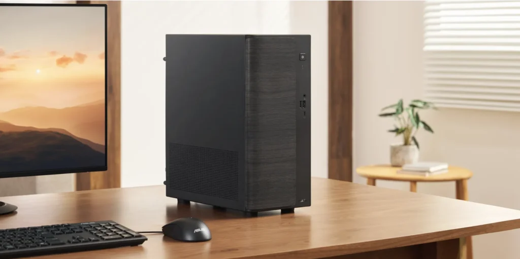 Black ASUS V500 Mini Tower desktop computer placed on a wooden desk with a monitor, keyboard, and mouse.