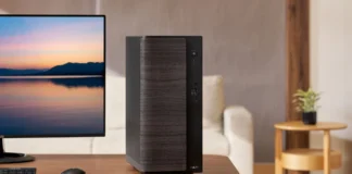 ASUS Launches V500 Mini Tower With Ryzen 7 260, Starts at €599 Black ASUS V500 Mini Tower desktop PC positioned beside an ASUS monitor in a modern home office environment.