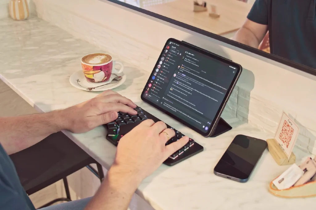 Dygma Releases Sonsei Travel-Friendly Ergonomic Mechanical Keyboard 4 Dygma Sonsei split keyboard connected to an iPad in a café workspace.